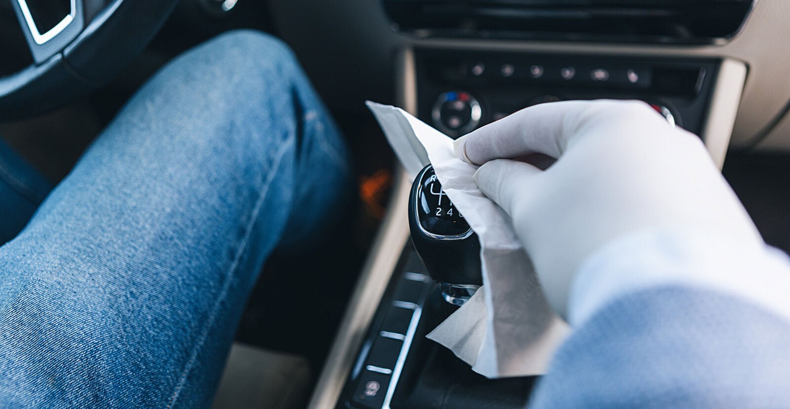 © rclassenlayouts Source: Getty Images Autofahrer desinfiziert den Schalthebel im Auto mit einem Tuch.