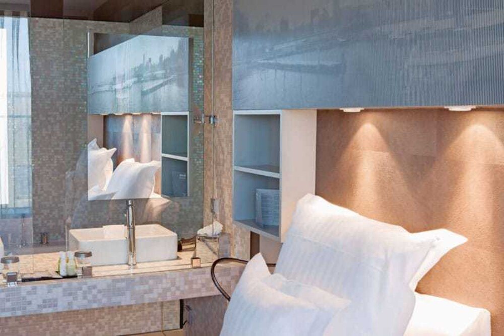 Raffiniert: Die teilweise verspiegelte Trennwand dient als Raumteiler und Sichtschutz zwischen Bett und Bad im Hotel Barcelo in Hamburg (D).
© Christoph Seelbach/Saint-Gobain Glass Deutschland Raffiniert: Die teilweise verspiegelte Trennwand dient als Raumteiler und Sichtschutz zwischen Bett und Bad im Hotel Barcelo in Hamburg (D).