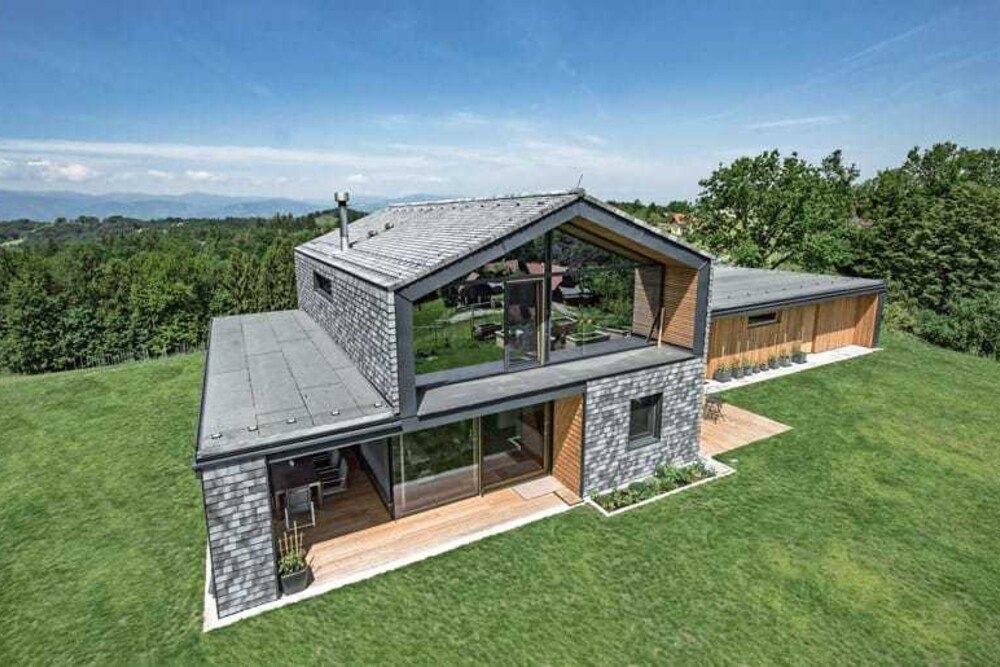 Die Kombination aus einer tragenden Fichtenholzkonstruktion, einem Steildach aus schiefergrauen Tondachziegeln sowie einer zweigeteilten Ziegel- und Lärchenholzfassade, ergänzt um große Glasflächen, verleiht dem Gebäude ein modernes und luftiges Aussehen.
© Wienerberger/Christa Strobl Die Kombination aus einer tragenden Fichtenholzkonstruktion, einem Steildach aus schiefergrauen Tondachziegeln sowie einer zweigeteilten Ziegel- und Lärchenholzfassade, ergänzt um große Glasflächen, verleiht dem Gebäude ein modernes und luftiges Aussehen.