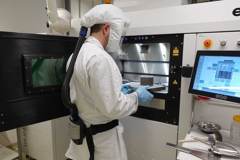 Ein Heraeus Mitarbeiter entnimmt das weltgrößte gedruckte Bauteil aus amorphen Metallen.
© Heraeus Ein Heraeus Mitarbeiter entnimmt das weltgrößte gedruckte Bauteil aus amorphen Metallen.