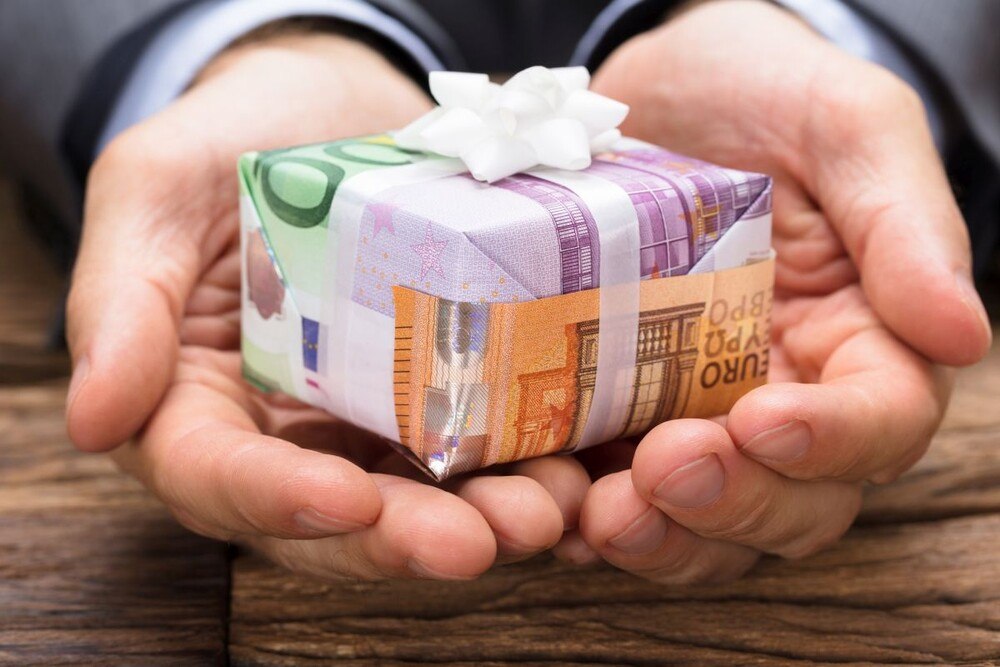 © Getty Images/AndreyPopov
Die Reputation von Unternehmern und Entscheidungsträgern kann durch Korruptionsvorwürfe sehr leicht und schnell beschädigt werden. , basic_html Ein Mann hält ein Geschenk mit einer Geldschein-Verpackung in seinen Händen