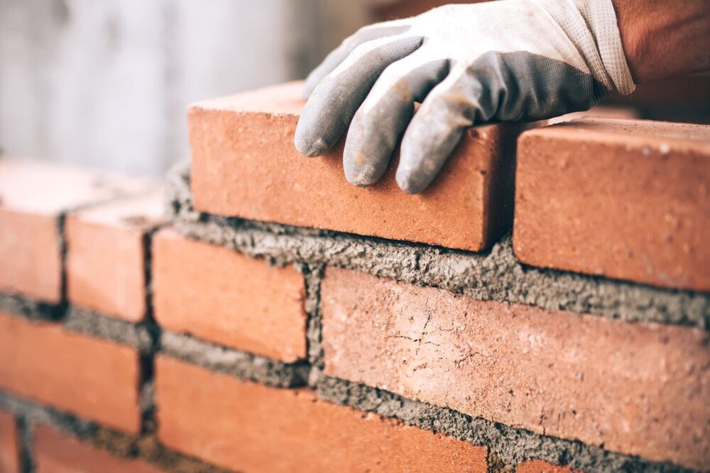 © Getty Images/Bogdanhoda Die Konjunkturdaten von Gewerbe und Handwerk haben sich erholt, vor allem bei den investitionsgüternahen Branchen läuft es sehr gut. Nahaufnahme eines Maurers bei der Montage einer Ziegelwand auf der Baustelle.