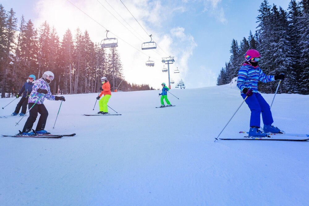 © iStock / Getty Images Plus / SerrNovik Kindergruppe fährt in einer Reihe Ski