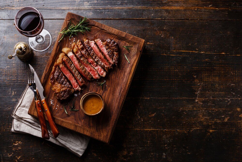Steak auf Holzbrett mit einem Glas Wein
© iStock / Getty Images Plus / Lisovskaya Steak auf Holzbrett mit einem Glas Wein