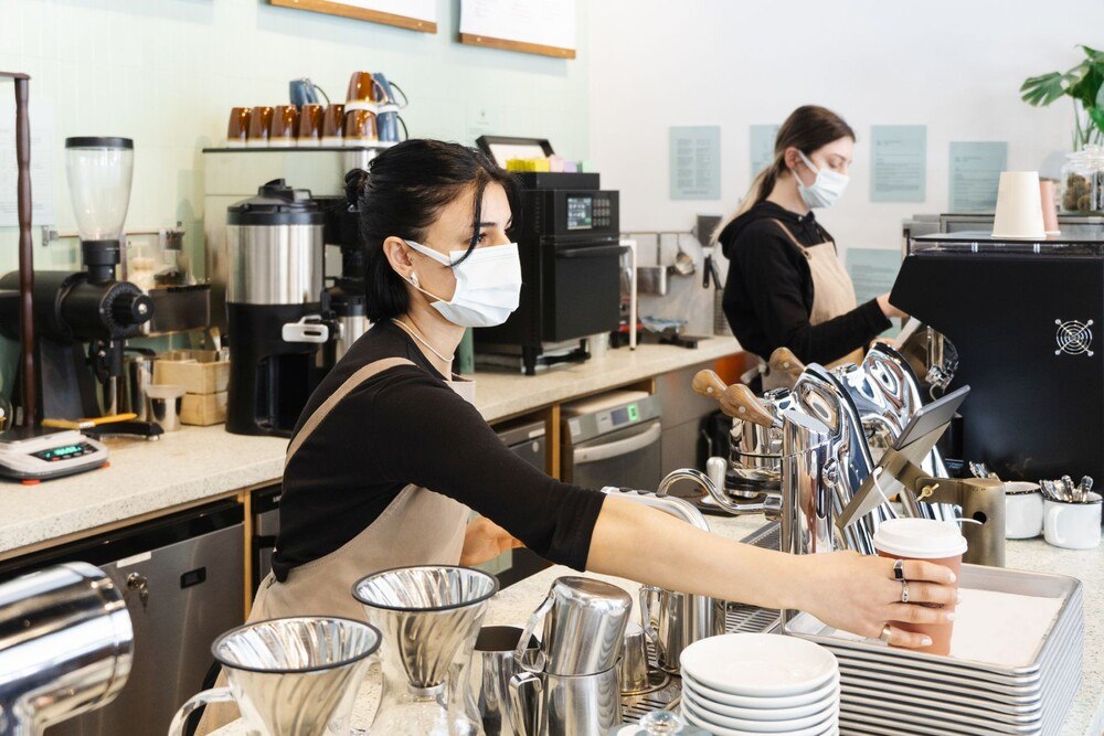 © iStock / Getty Images Plus / Yazgi Bayram Servicepersonal schenkt Kaffee aus.