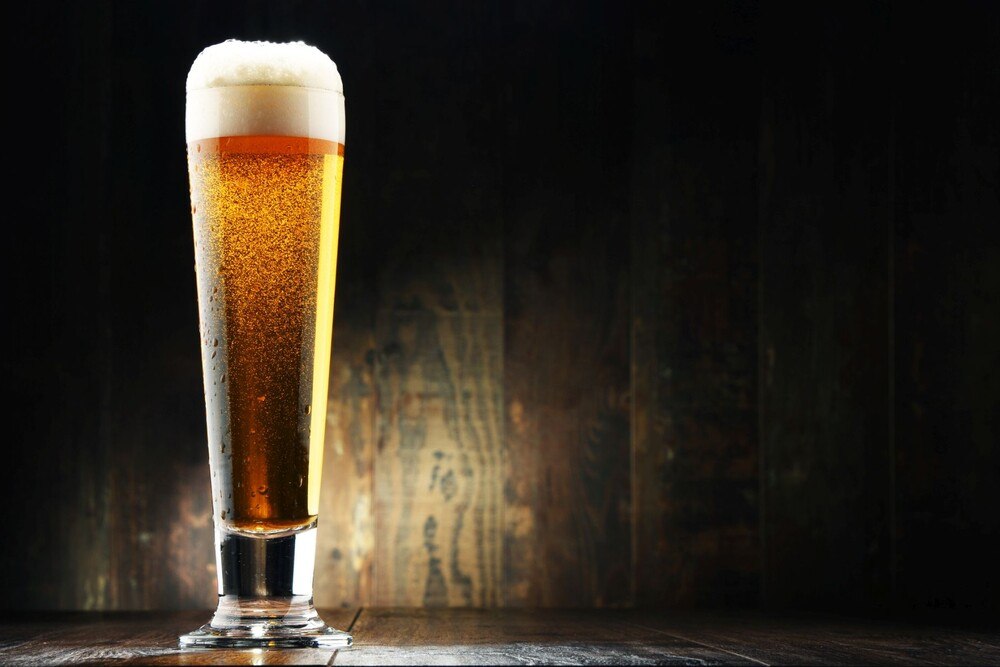 © iStock / Getty Images Plus / monticelllo Komposition mit einem Glas Pils auf hölzernen Hintergrund