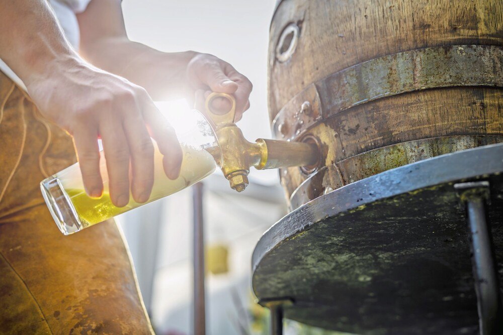 © iStock / Getty Images Plus / Anselm Kempf Eine Person zapft Bier aus einem Holzfass.