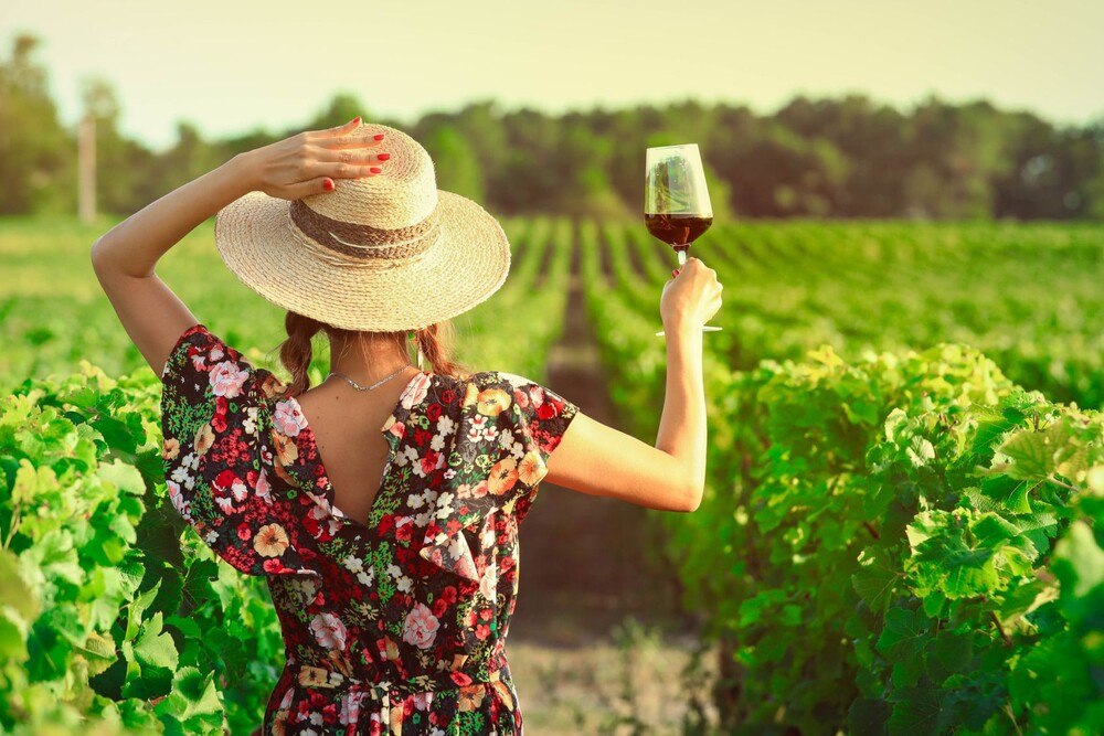 © iStock / Getty Images Plus / EoNaYa Frau mit Weinglas steht im Weinberg