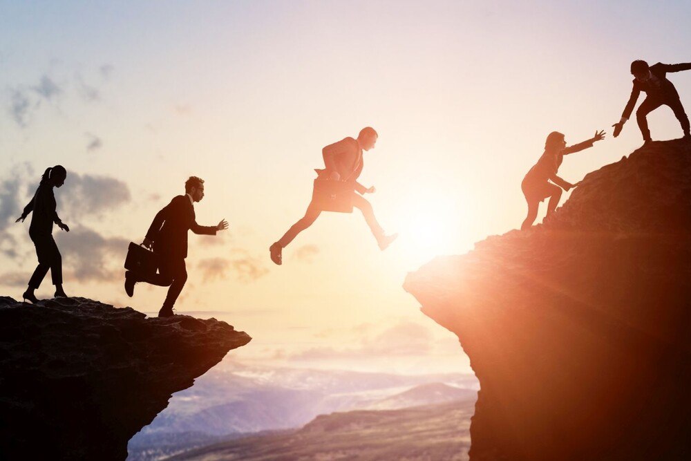 © iStock / Getty Images Plus / metamorworks Gruppe von Geschäftsleuten, die einen Berg erklimmen.