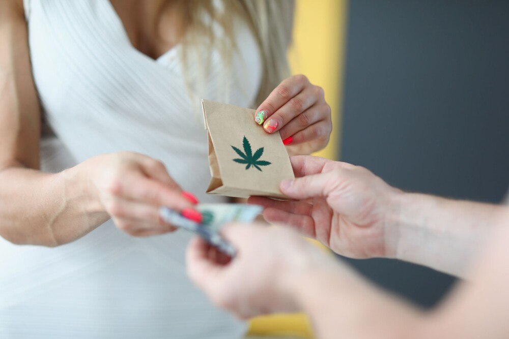 © iStock / Getty Images Plus / megaflopp Frau gibt Geld und erhält Beutel Marihuana