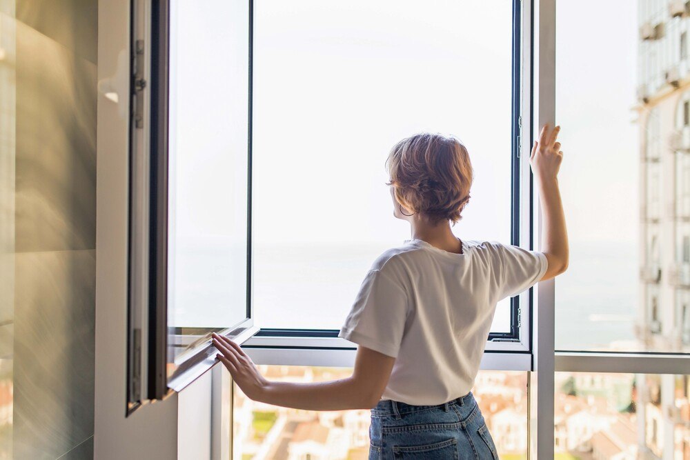 © getty images/ dangrytsku Frau öffnet Fenster zum Lüften eines Raumes