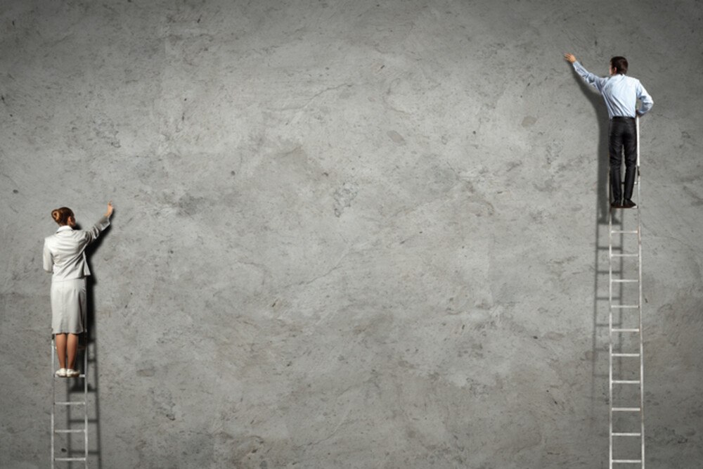 © SergeyNivens iStock / Getty Images Plus Frau steht auf deutlich niedrigerer Leiter als Mann