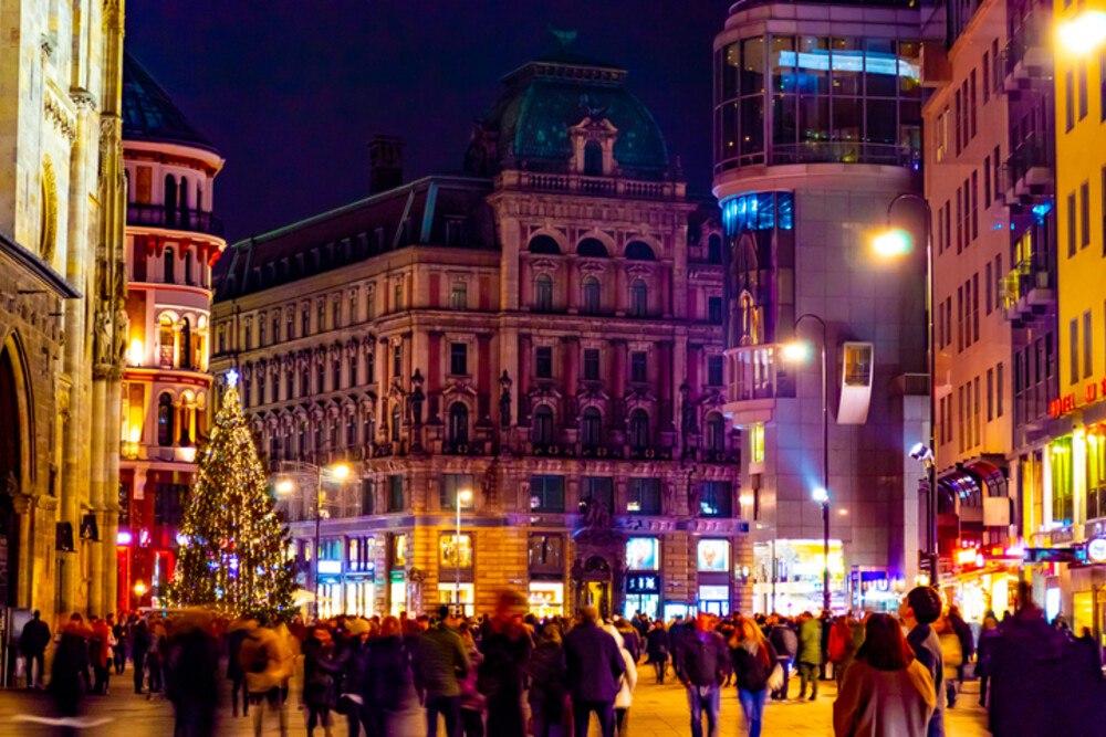 © iStock / Getty Images Plus / Sergiy Katrych
Die Geschenkeeinkäufe präsentieren sich zwar auch heuer im Durchschnitt betrachtet als weitgehend krisenresistent, eine differenzierte Sichtweise ist jedoch angebracht.
Weihnachtszeit. Wien. Die Menschen gehen um den Platz herum, in der Mitte des quadratischen Weihnachtsbaums. Schöne antike Architektur. Kathedrale im gotischen Stil. Eine große Anzahl von Tourist*innen