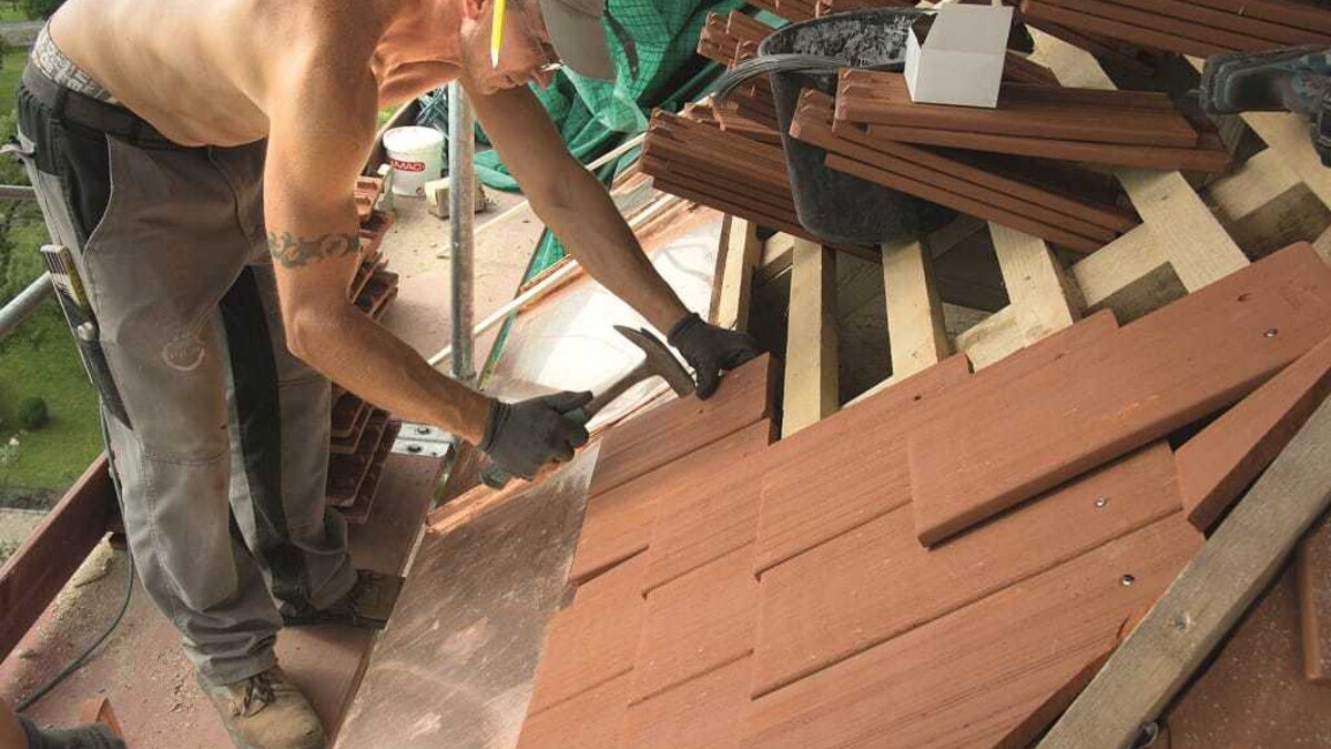Mitarbeiter der Firma ­Hintenberger Dächer u. Holzbau GmbH bei der Verlegung der ersten Reihe an der Traufe. An den Walmgraten war viel Feinschnitt erforderlich.