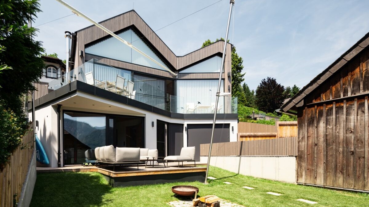 Blick vom See auf das Wohnhaus mit seinen zwei Geschossen und den beiden vorgelagerten Terrassen. 
