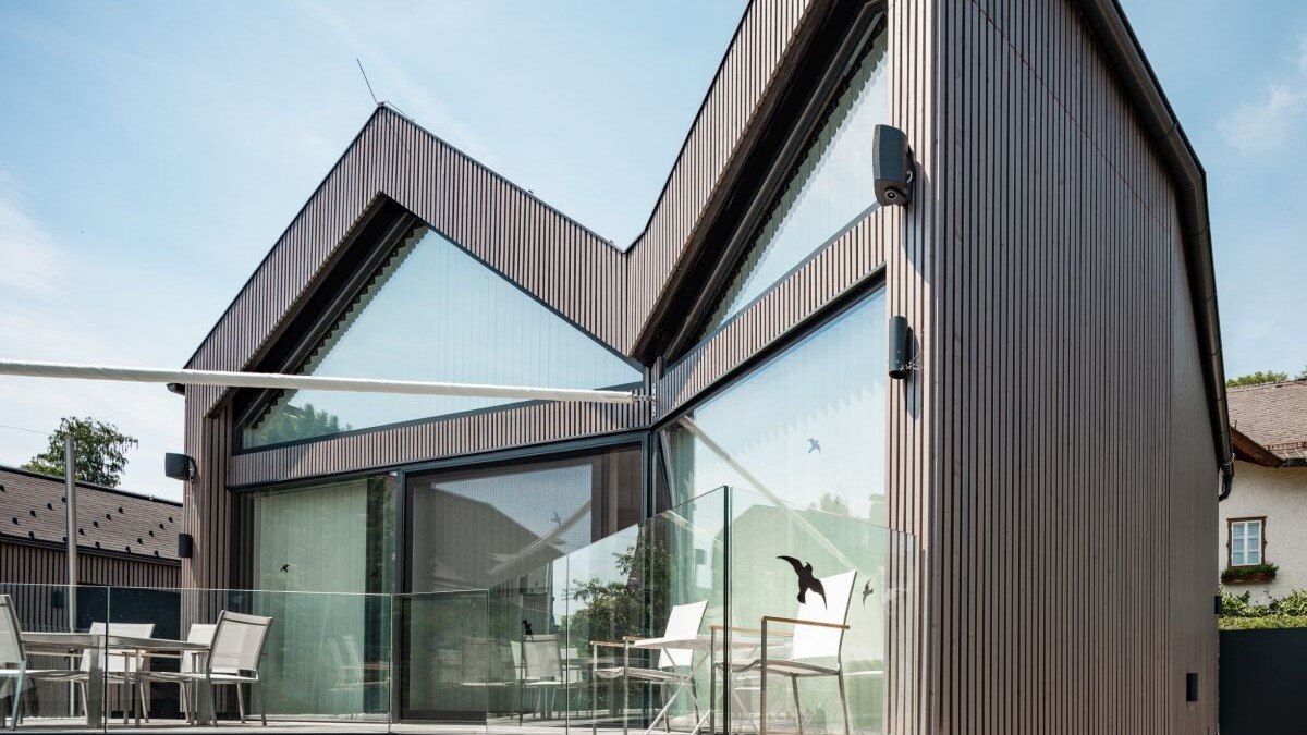 Seitenansicht des Erdgeschosses mit seinen großflächigen Glasfronten und die Terrasse.