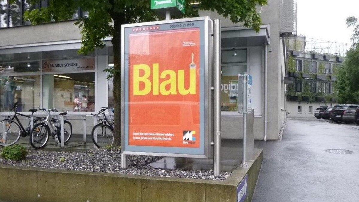 Das Werbesujet auf rotem Grund der neuen Werbekampagne der Salzburger Malerinnung in der Alpenstraße, Ecke Friedenstraße.