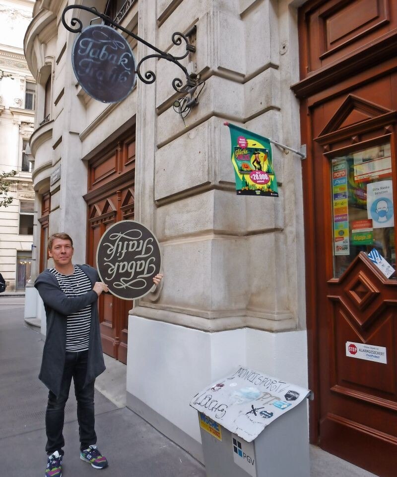 © Redaktion Stefan Binder mit seinem neuen Trafik-Schild für das Gebäude, in dem sein Geschäft liegt – ein üblicher beleuchteter Rauchring käme nicht infrage. Aufhängen wird er das Schild aber richtig herum ...