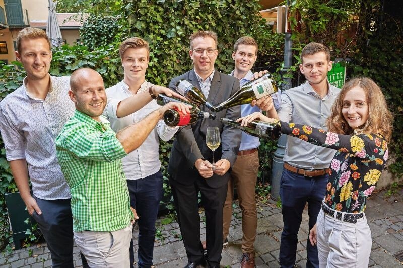 © Herbert Lehmann Die sechs Finalisten der Jungwinzertrophy im Wiener Schlossquadrat schenken dem Hausherren, Jürgen Geyer (Mitte), ein.