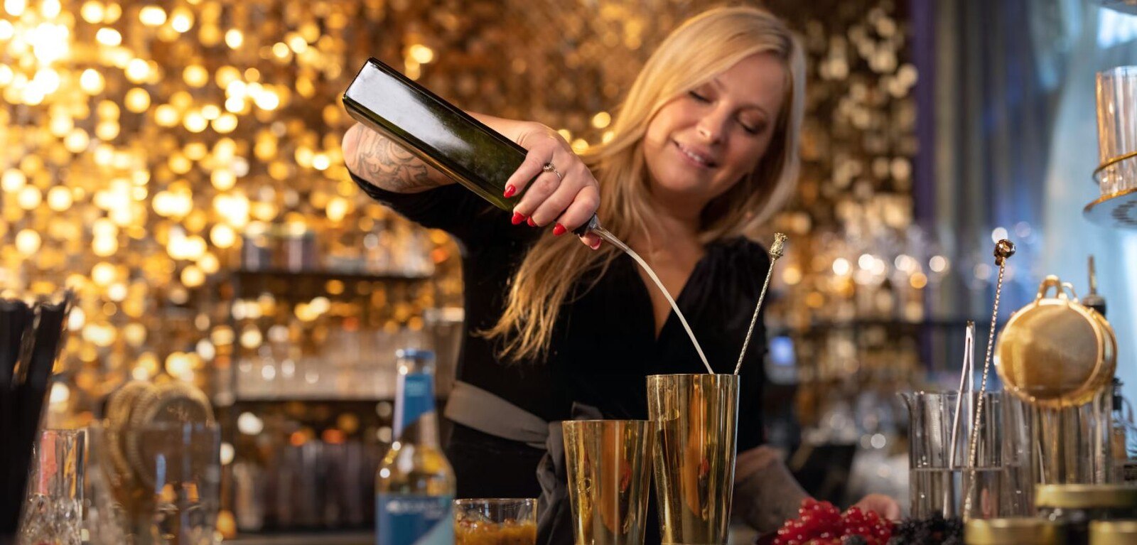 Barfrau Isabella Lombardo gießt einen Drink in ein Longdrinkglas.