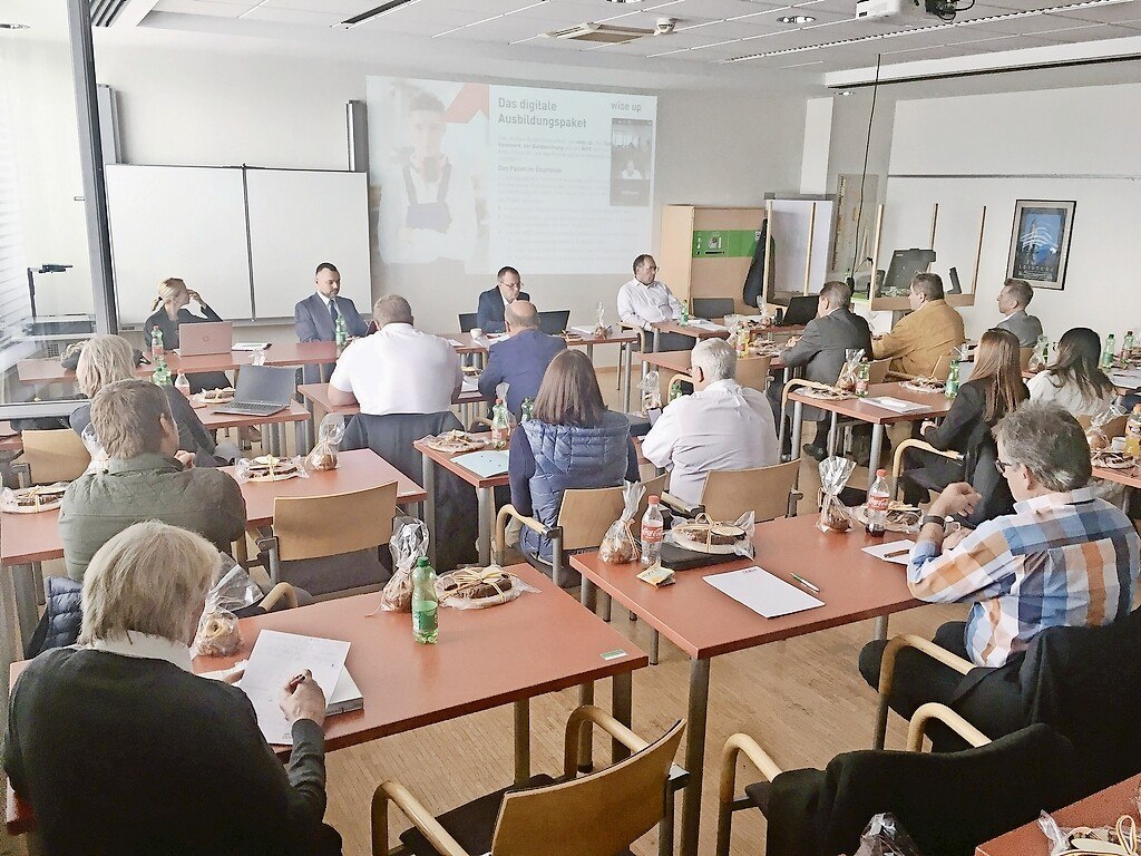 formell gekleidete Menschen sitzen an Tischen mit Kuchen und Getränken