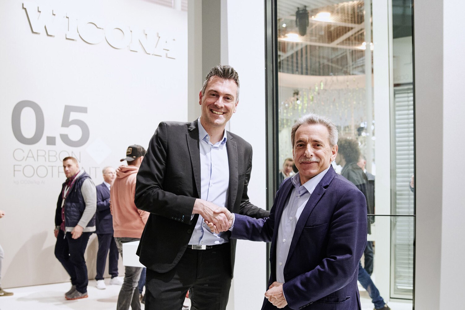 Besiegeln ihre Partnerschaft für nachhaltige Fassaden: Bruno Mauvernay (l.), Direktor des Geschäftsbereichs Glasfassaden bei Saint-Gobain und Henri Gomez (r.), Vice President bei Hydro Building Systems.