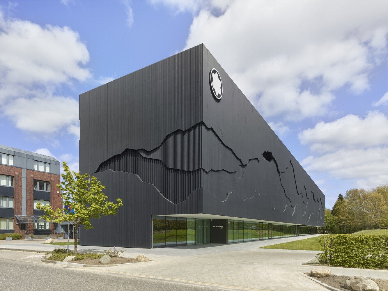 Auch in der Seitenansicht des Gebäudes kann man die Glasfassade hinter dem architektonisch inszenierten Fassadeneinschnitt erahnen.
