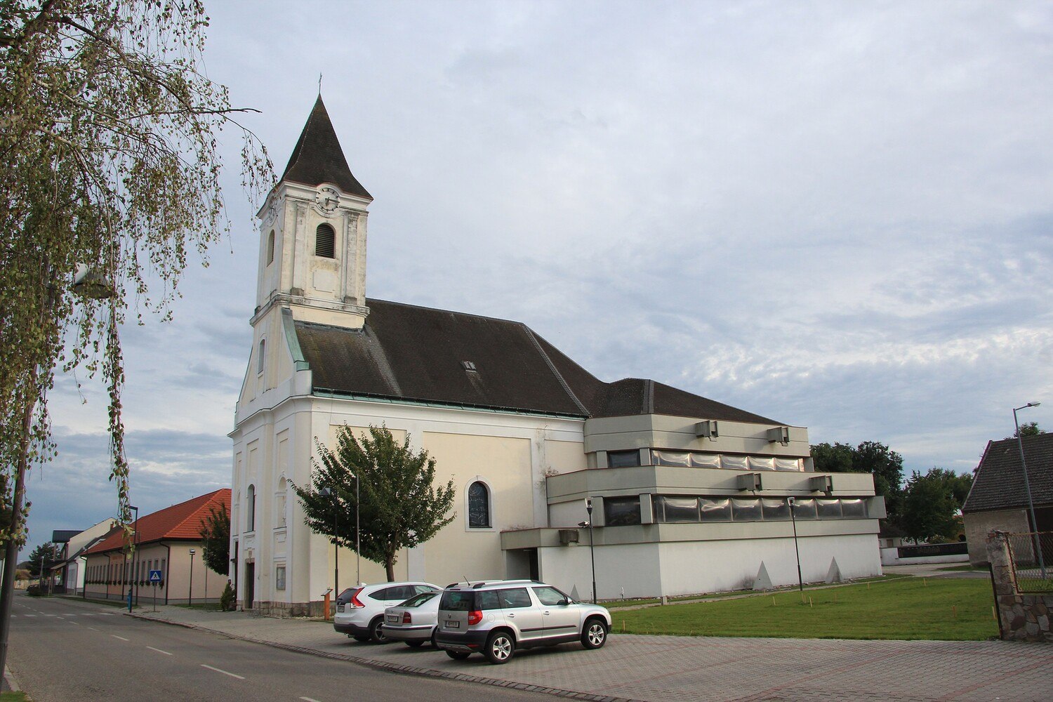 Gesamtansicht der katholischen Pfarrkirche hl. Margaretha in der burgenländischen Gemeinde Apetlon mit dem Zubau und den gewölbten Plexiglasfenstern im Originalzustand.