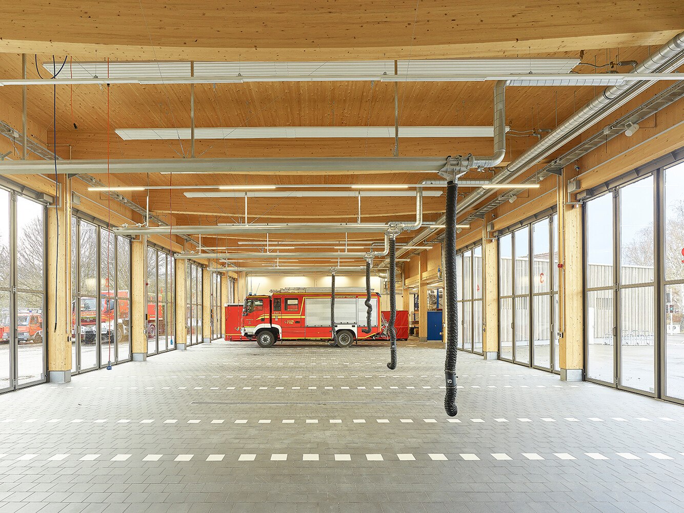 Das Tragwerk der Fahrzeughalle bilden "Trägern auf zwei Stützen" in Reihung, das heißt Brettschichtholz-Träger in Fischbauchform auf Brettschichtholz-Stützen.