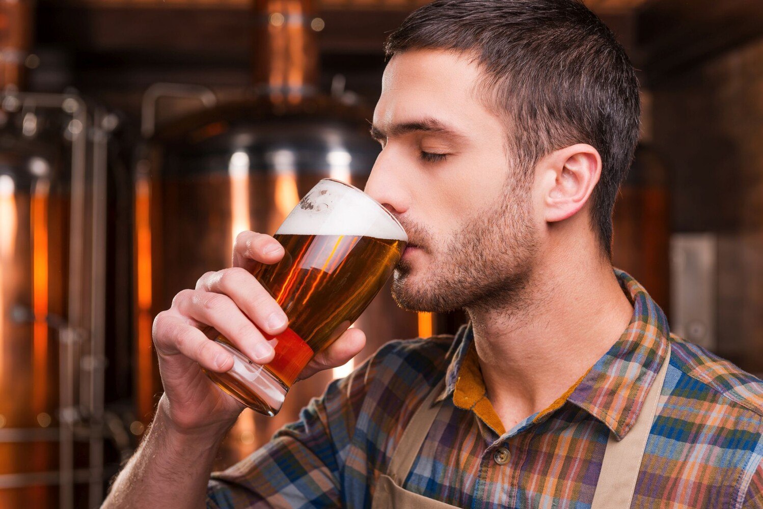 © iStock / Getty Images Plus / g-stockstudio
Da steht er, der junge Braumeister – Schürze stramm, Augen zu und Mund voll Bier. Inmitten seines Sudhauses testet er seine neueste Kreation. Kein offizielles Jury-Mitglied, aber wer braucht schon Titel, wenn man Geschmack hat? Wer weiß, vielleicht mischt er beim nächsten BeerTasting Community Award mit – als Genießer hat er ja schon mal das richtige Training.
Bier trinken