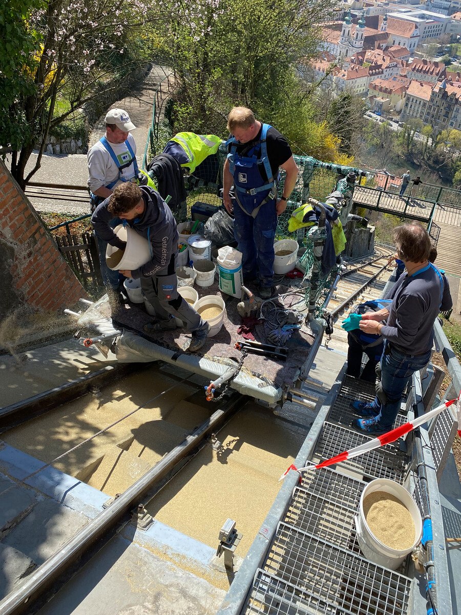 Zur Herstellung der rutschhemmenden Fläche zu Wartungszwecken wurde die frische Abdichtungsschicht mit Quarzsand abgestreut. Der Materialtransport erfolgte über eine eigens für das Sanierungsprojekt angefertigten Draisine. 