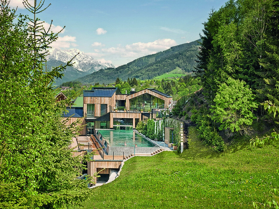 Naturhotel Forsthofgut Leogang Aussenansicht mit Wiese und Pool