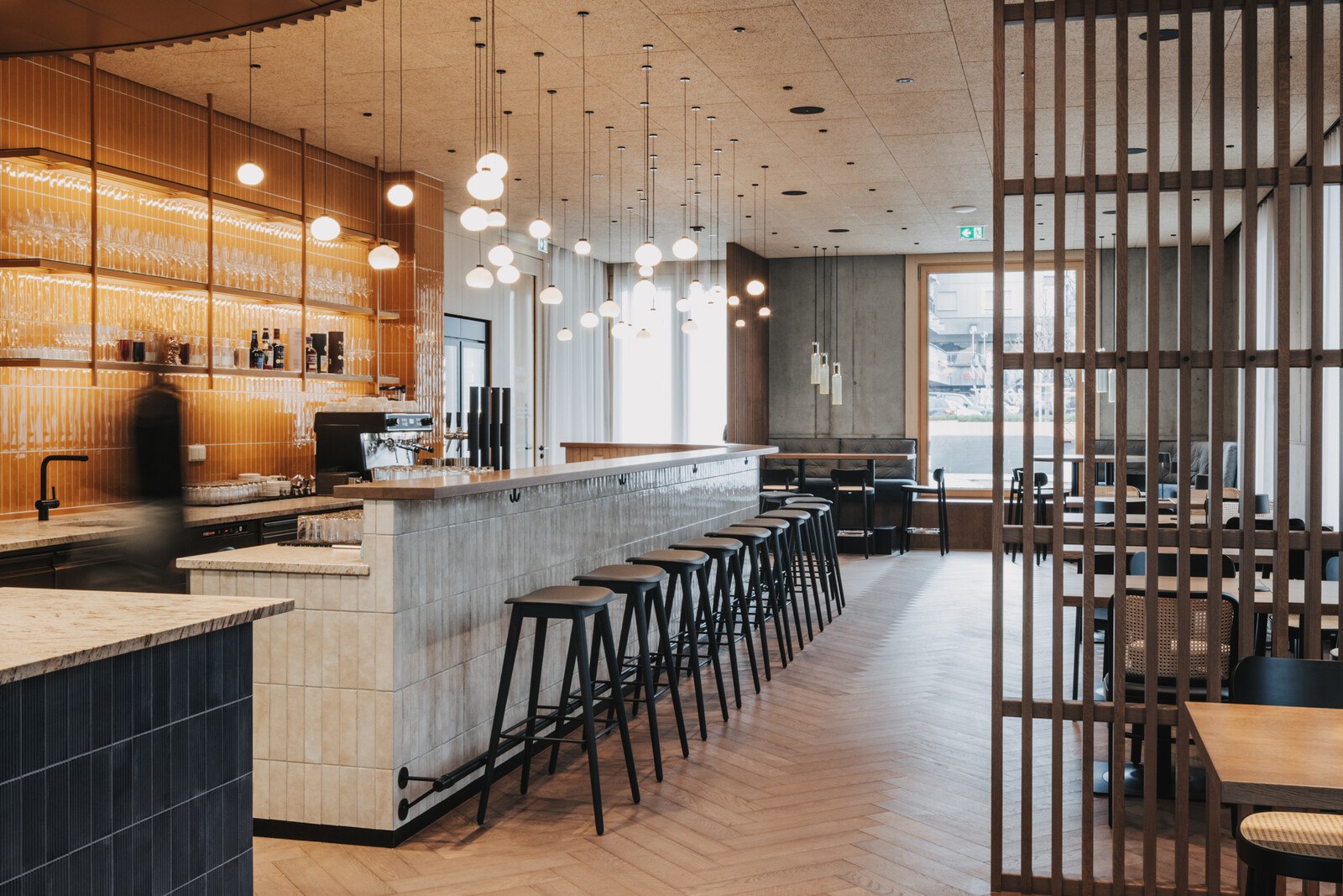 Heller Innenraum des Restaurants "Sarah Kocht". Links die Bar, rechts Tische.