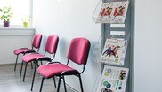 Mit rotem Stoff bezogene Sessel und ein Zeitschriftenständer im Wartebereich einer der Beratungsstellen. in 