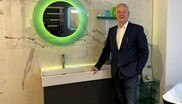 Mann posiert vor Waschbecken und Spiegel.