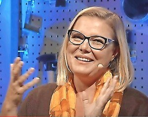 Kathrin Steiner-Hämmerle gestikulierend und lächelnd mit Brille und orangenem Schal