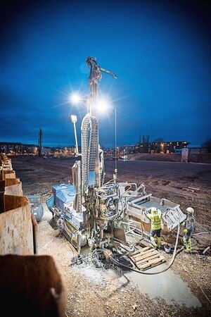 Maschine auf Baustelle, die Erdwärmesonden einsetzt, mit einem Bauarbeiter