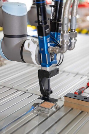 Bei Bader Glastechnologie bringen die Cobots Befestigungselemente auf Glasscheiben an.