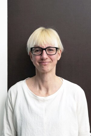 Frau mit blonden Haaren und schwarzer Brille