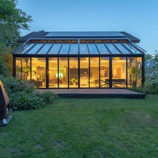 Der Wintergarten wurde bei dem Haus aus den 70er-Jahren zur neuen Außenfassade. Der Wohnraum kann mit der Glas-Faltwand einfach mit dem Garten verbunden werden.