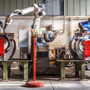 Roboterarm und Mensch arbeiten beim Schweißen zusammen