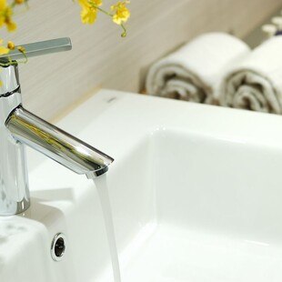 Teilansicht eines weißen Waschbeckens mit Wasserhahn