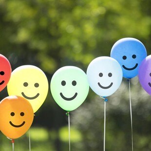 Sieben bunte Luftballone mit Smiley-Gesichtern