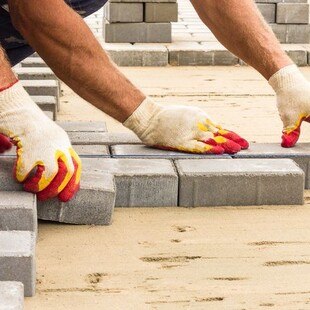 © nnorozoff / iStock / Getty Images Plus Arbeiter beim Pflastersteine legen