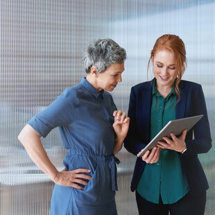 © PeopleImages iStock Getty Images Plus Zwei Frauen, eine hält einen Tablet PC