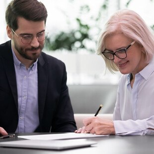 © fizkes iStock Getty Image Plus eine ältere Dame und ein Herr sprechen über Papiere am Tisch