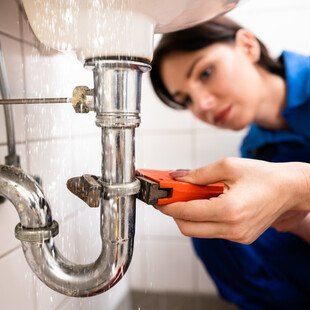 Klempnerin repariert Rohr beim Waschbecken